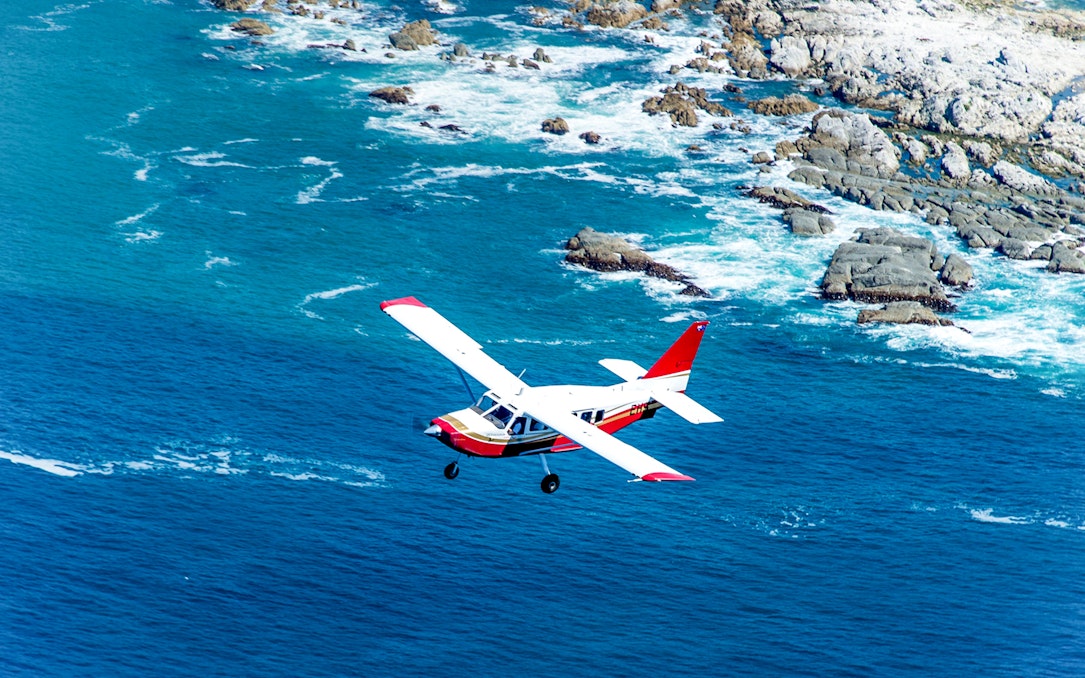 Small plane flying over Kaikoura coastline, New Zealand.