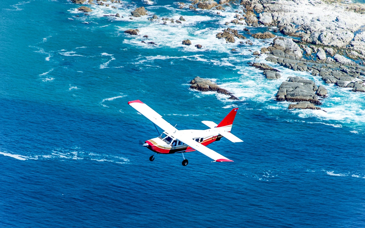 Small plane flying over Kaikoura coastline, New Zealand.