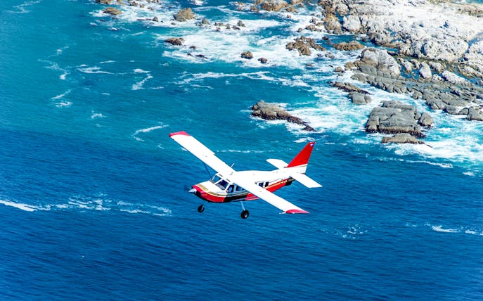 Small plane flying over Kaikoura coastline, New Zealand.