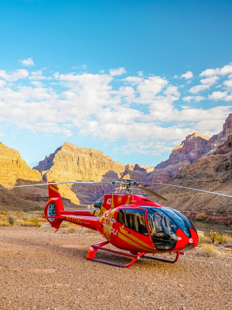 Helicopter on the Grand Canyon floor with canyon walls in the background.