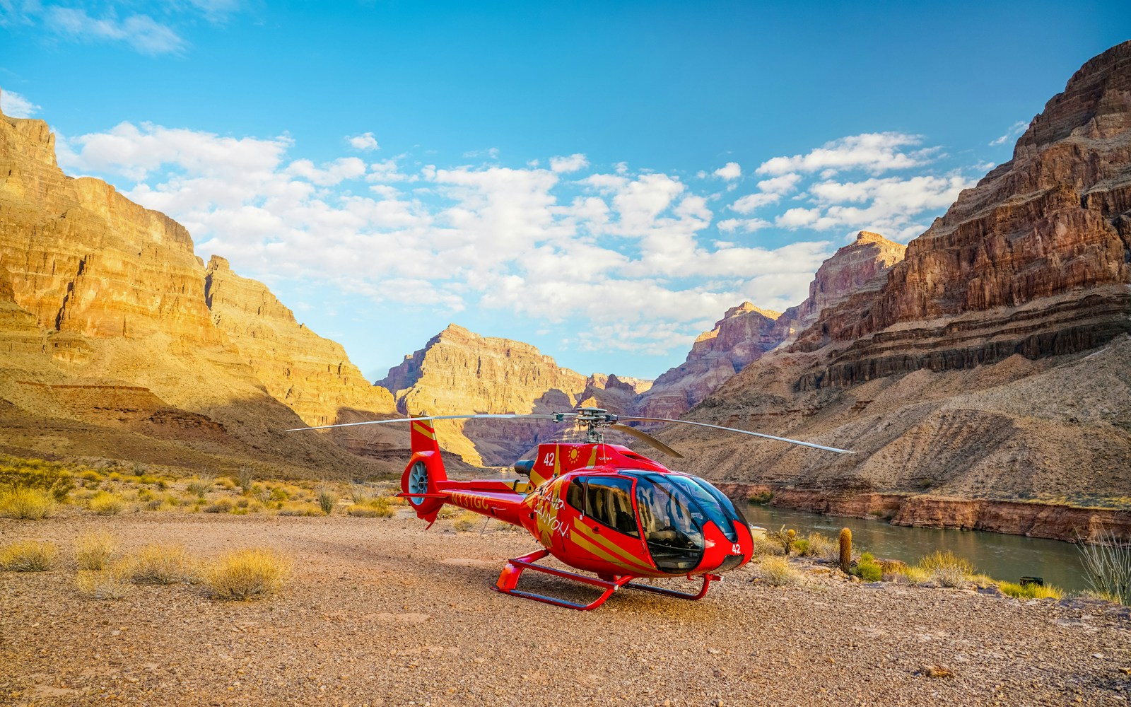 Helicopter on the Grand Canyon floor with canyon walls in the background.