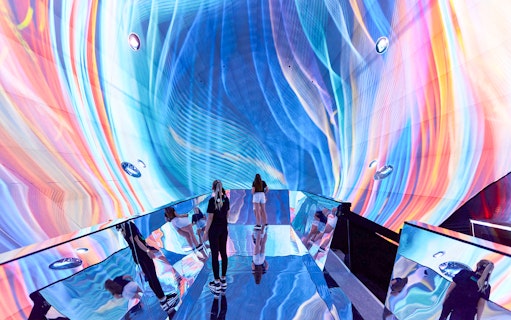 Visitors exploring vibrant light display at Journey Exhibit, Light Art Museum.