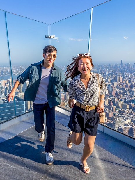 Visitors enjoying the view from an observation deck in New York City with the Empire State Building in the background.