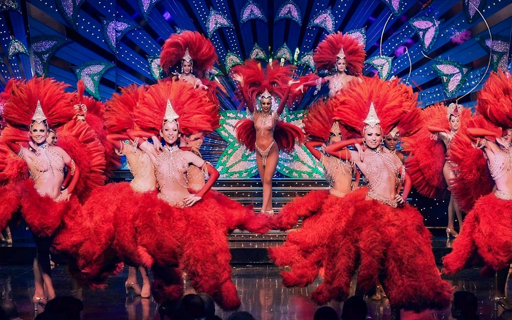 Dancers in red feather costumes performing at Moulin Rouge, Paris.