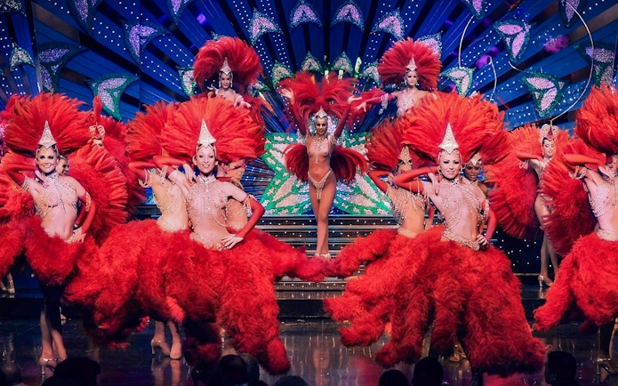 Dancers in red feather costumes performing at Moulin Rouge, Paris.