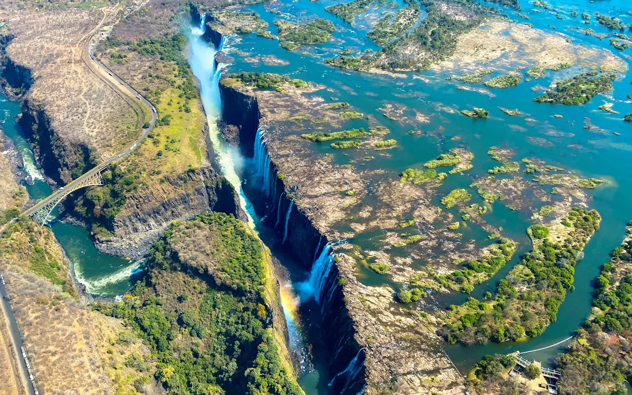 Aerial view of Victoria Falls with surrounding landscape and Zambezi River.