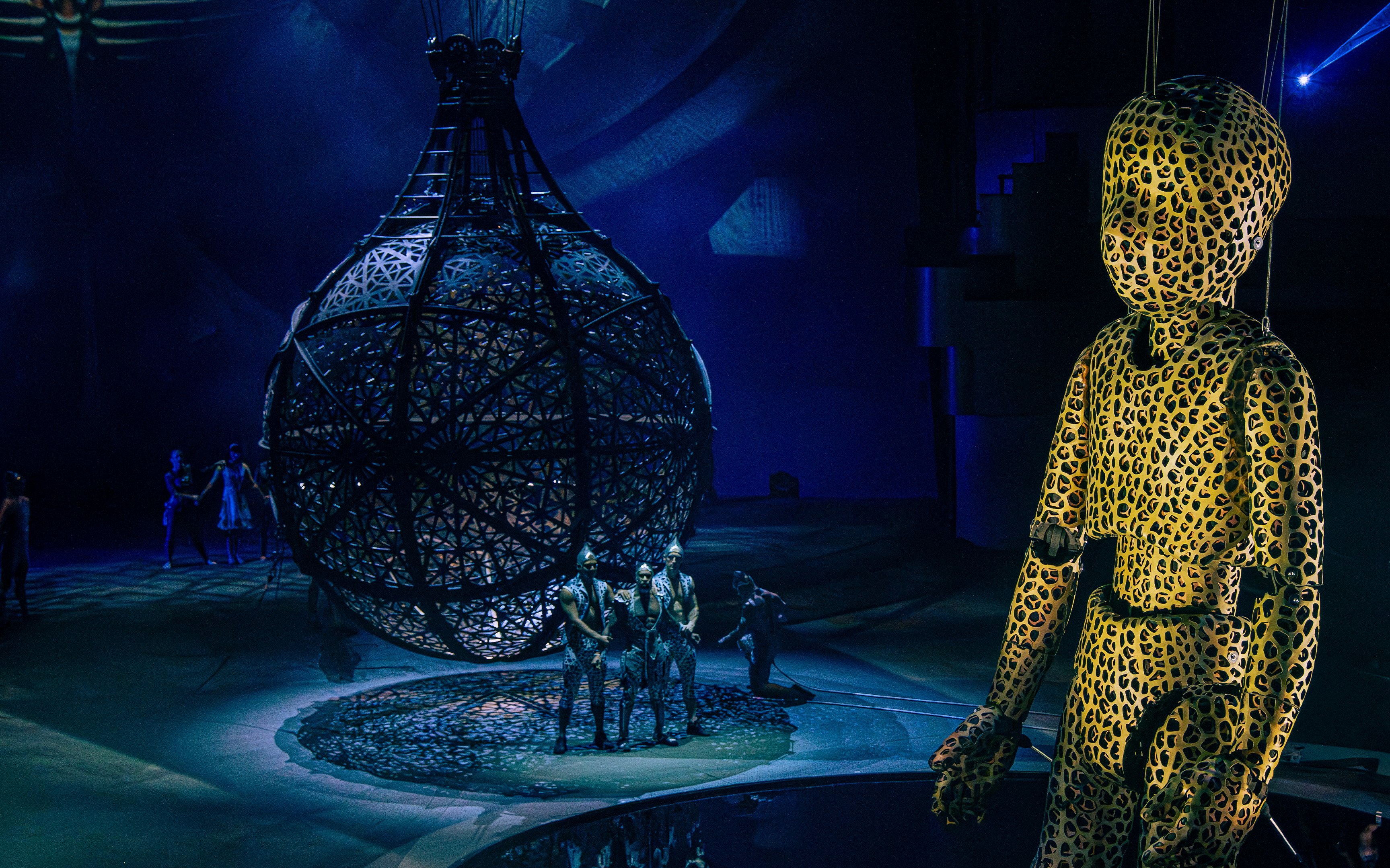 Performers in intricate costumes with a large spherical structure at La Perle show, Dubai.