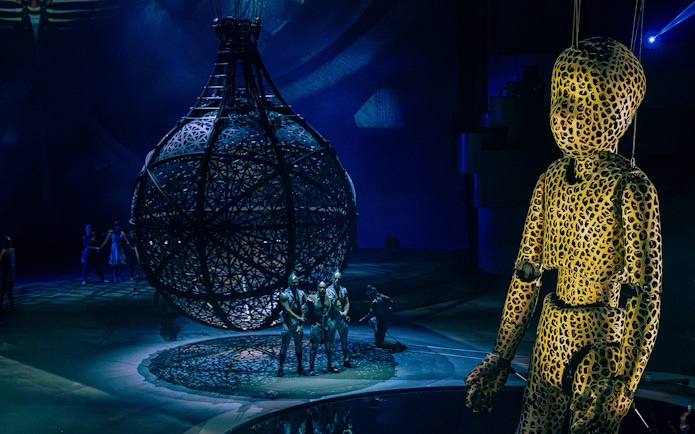 Performers in intricate costumes with a large spherical structure at La Perle show, Dubai.