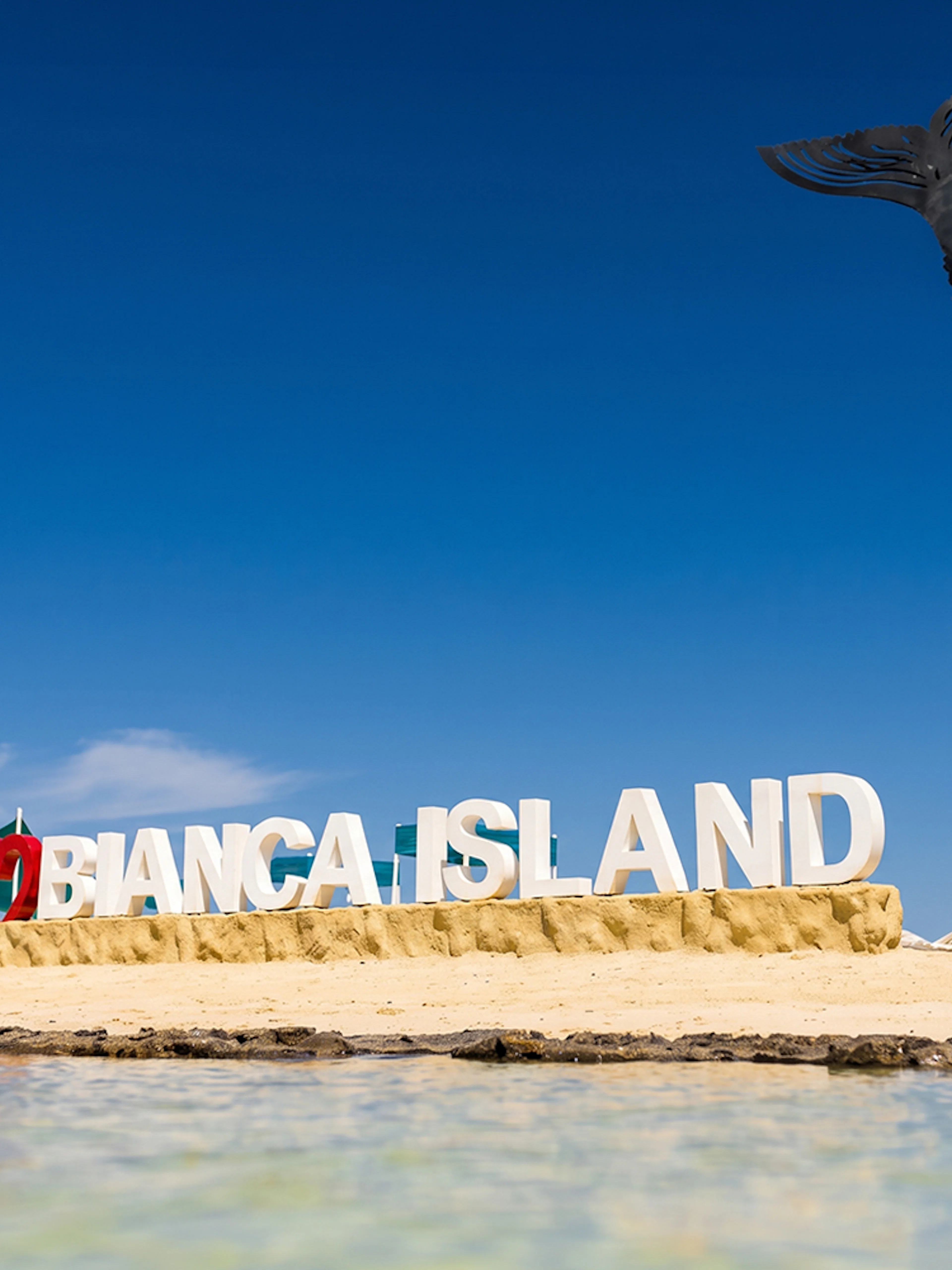 Bianca Island sign on sandy beach with fish sculpture, Hurghada tour.