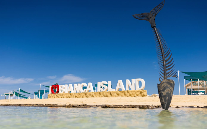 Bianca Island sign on sandy beach with fish sculpture, Hurghada tour.