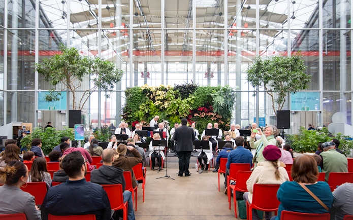 Orchestra performing at California Academy of Sciences with audience seated in red chairs.