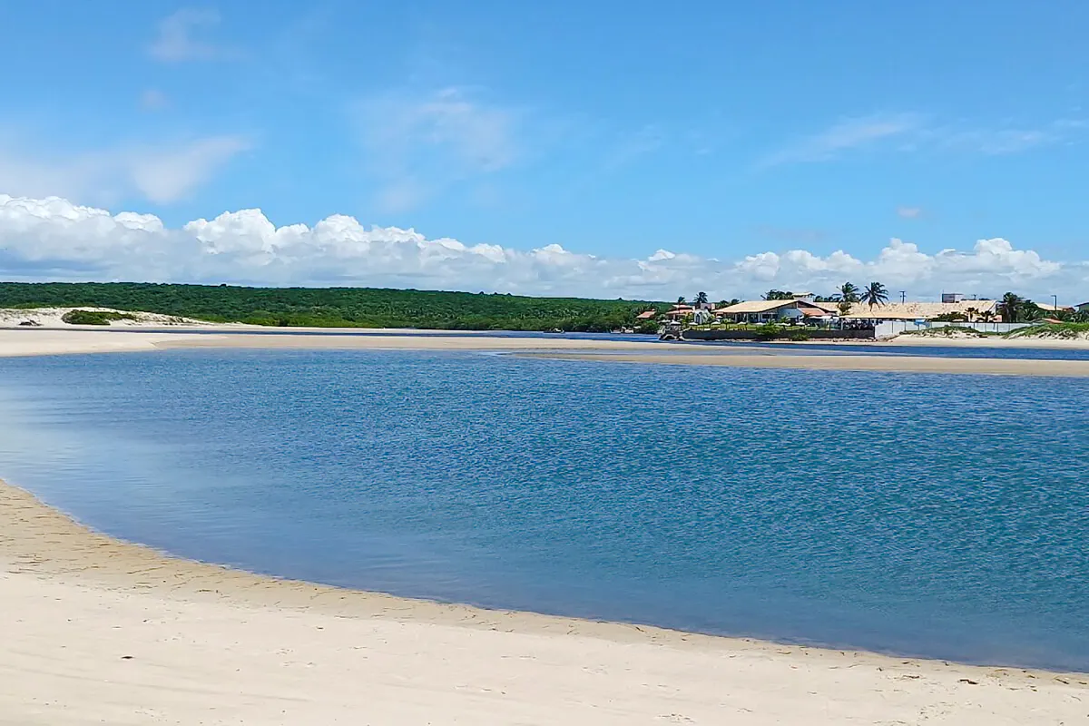 Natural pools at Águas Belas beach with distant village, Sao Paulo.