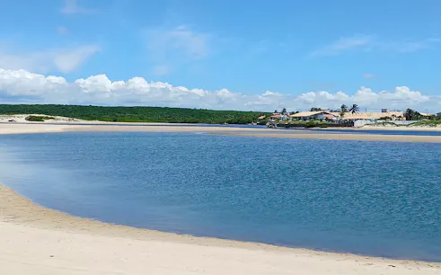 Natural pools at Águas Belas beach with distant village, Sao Paulo.