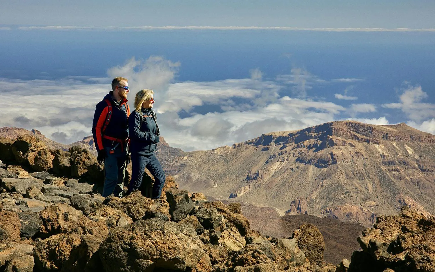 Couple hiking on rocky terrain with Mount Teide in the background, Tenerife.