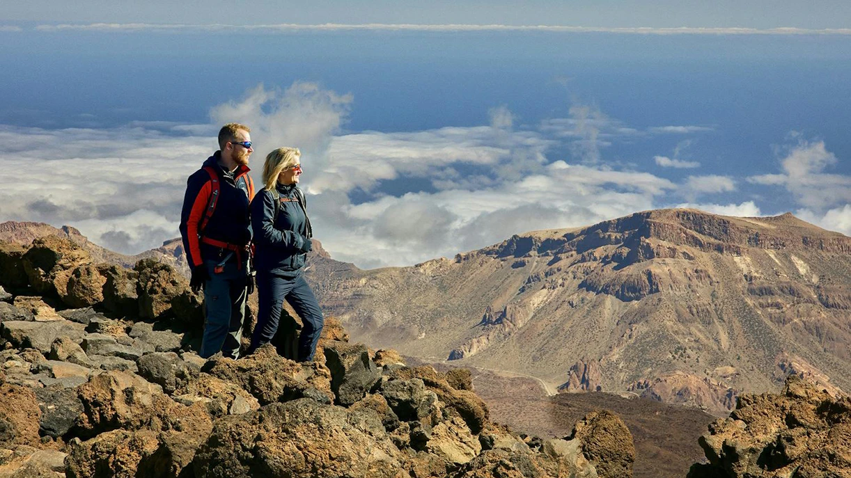 Couple hiking on rocky terrain with Mount Teide in the background, Tenerife.