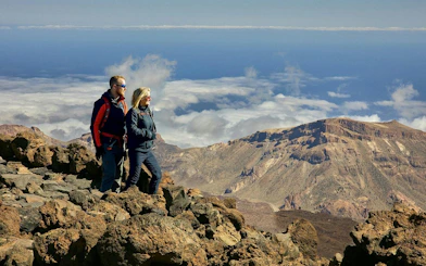 Couple hiking on rocky terrain with Mount Teide in the background, Tenerife.