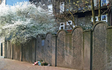 Ghetto wall fragment in Krakow with memorial flowers at the base.