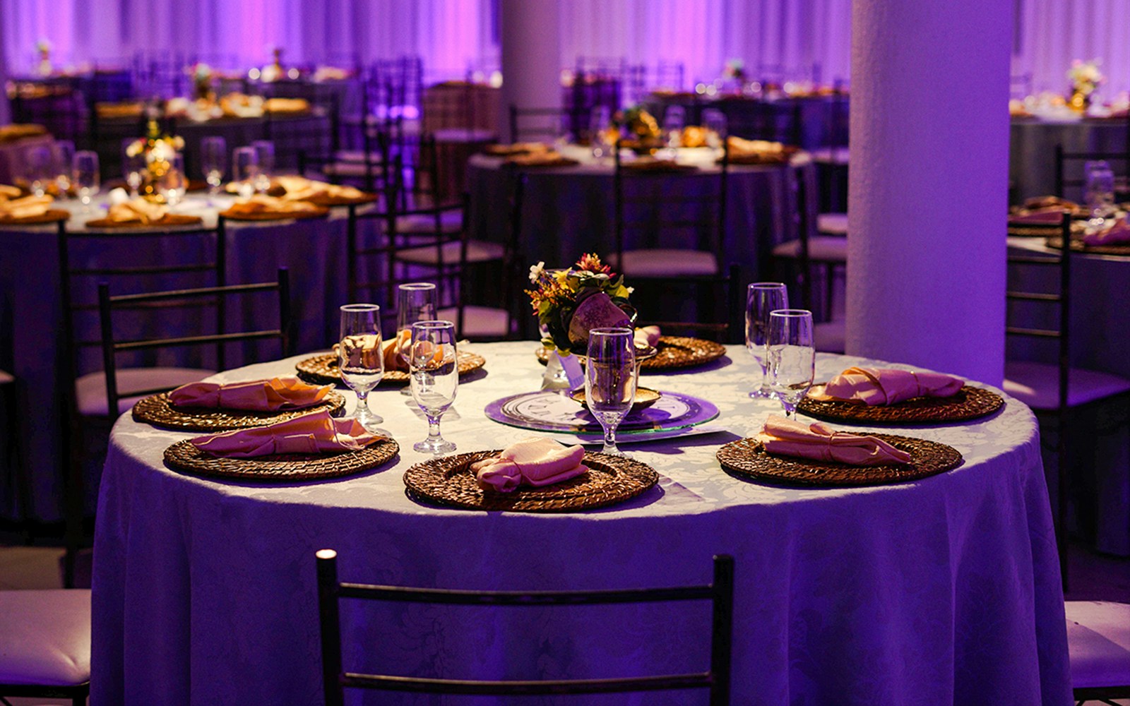 Dinner table set with plates, glasses, and napkins in an elegant event setting.