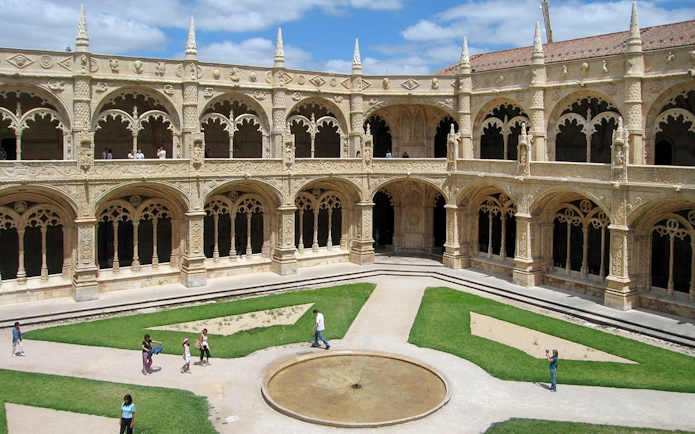 Jeronimos Monastery courtyard garden with ornate arches and central fountain, Lisbon.