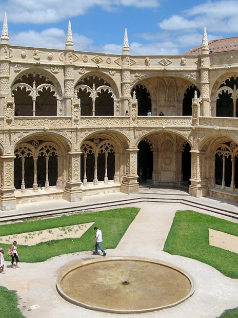 Jeronimos Monastery courtyard garden with ornate arches and central fountain, Lisbon.