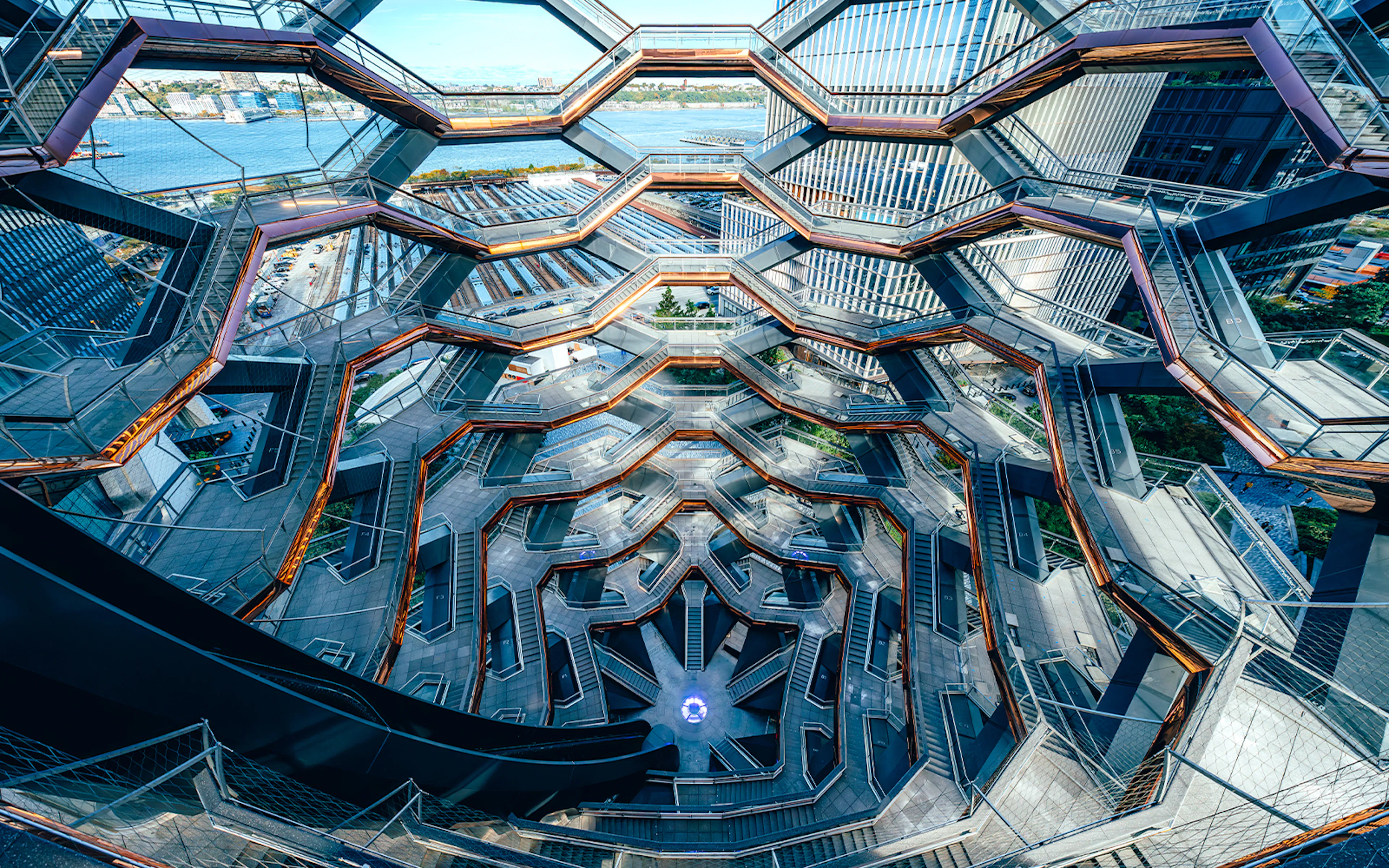 Vessel's intricate staircases and platforms in New York City with river view.