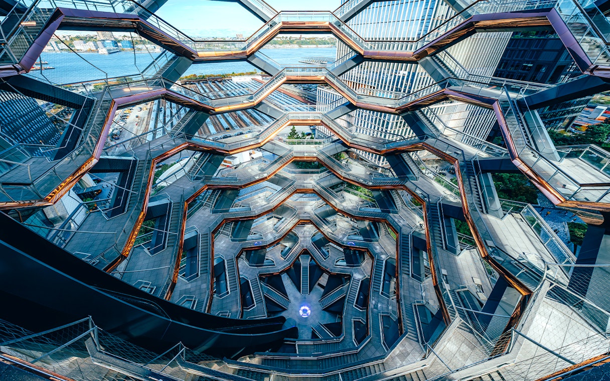 Vessel's intricate staircases and platforms in New York City with river view.
