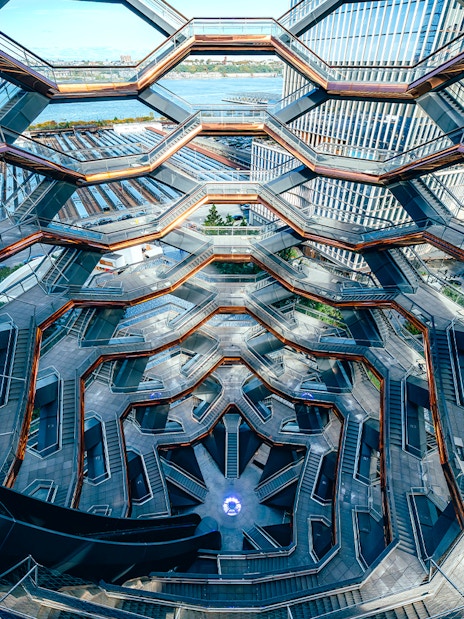 Vessel's intricate staircases and platforms in New York City with river view.