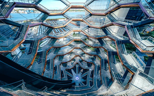 Vessel's intricate staircases and platforms in New York City with river view.