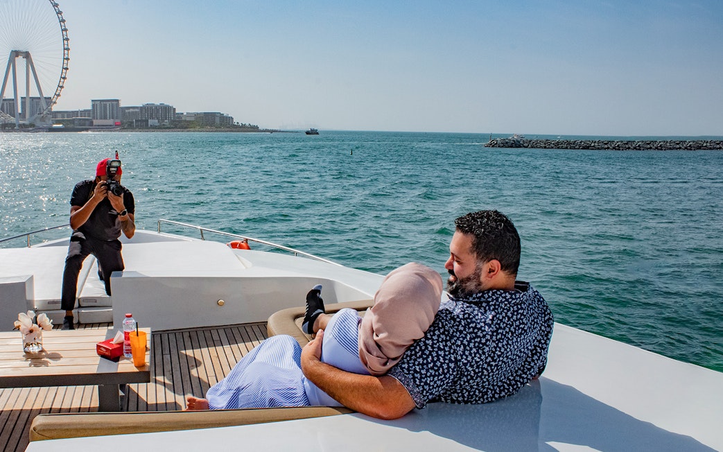 Tourists on Superyacht TriDeck Cruise taking photos with Dubai skyline in background.