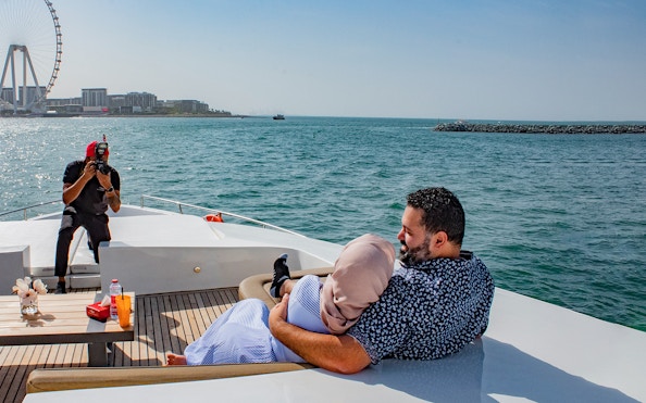 Tourists on Superyacht TriDeck Cruise taking photos with Dubai skyline in background.