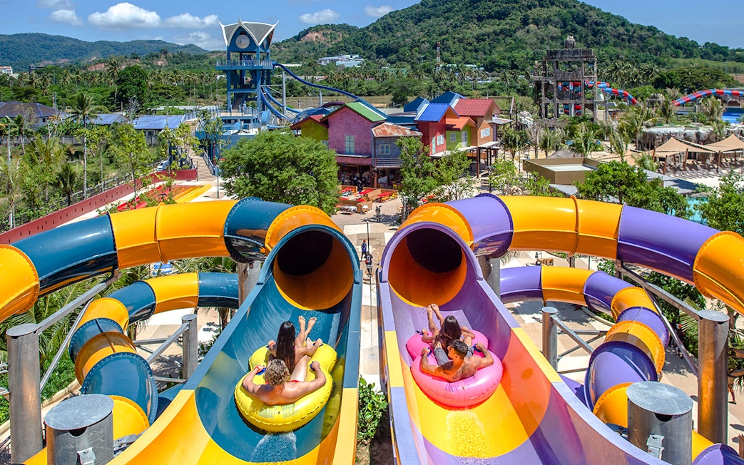 Visitors on inflatable tubes at the top of a colorful waterslide at Andamanda Phuket.