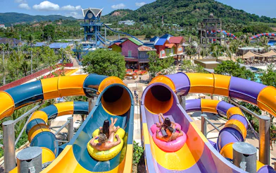 Visitors on inflatable tubes at the top of a colorful waterslide at Andamanda Phuket.
