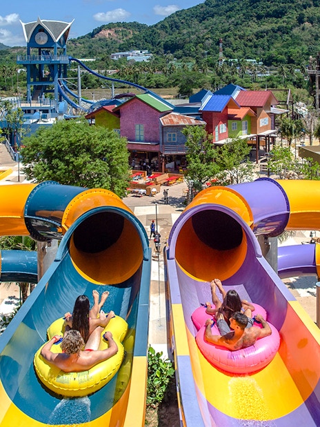 Visitors on inflatable tubes at the top of a colorful waterslide at Andamanda Phuket.