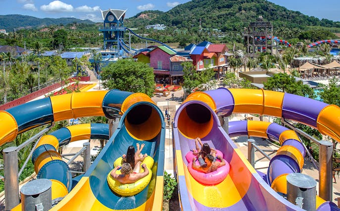 Visitors on inflatable tubes at the top of a colorful waterslide at Andamanda Phuket.