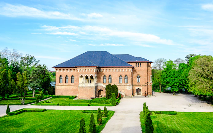 Mogosoaia Palace in Romania surrounded by lush gardens and trees.