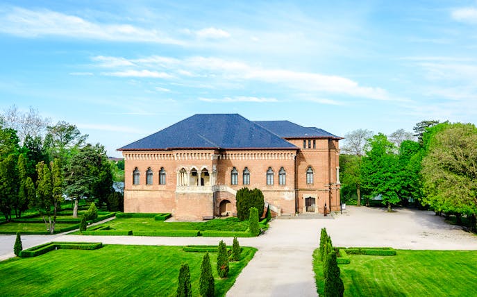 Mogosoaia Palace in Romania surrounded by lush gardens and trees.