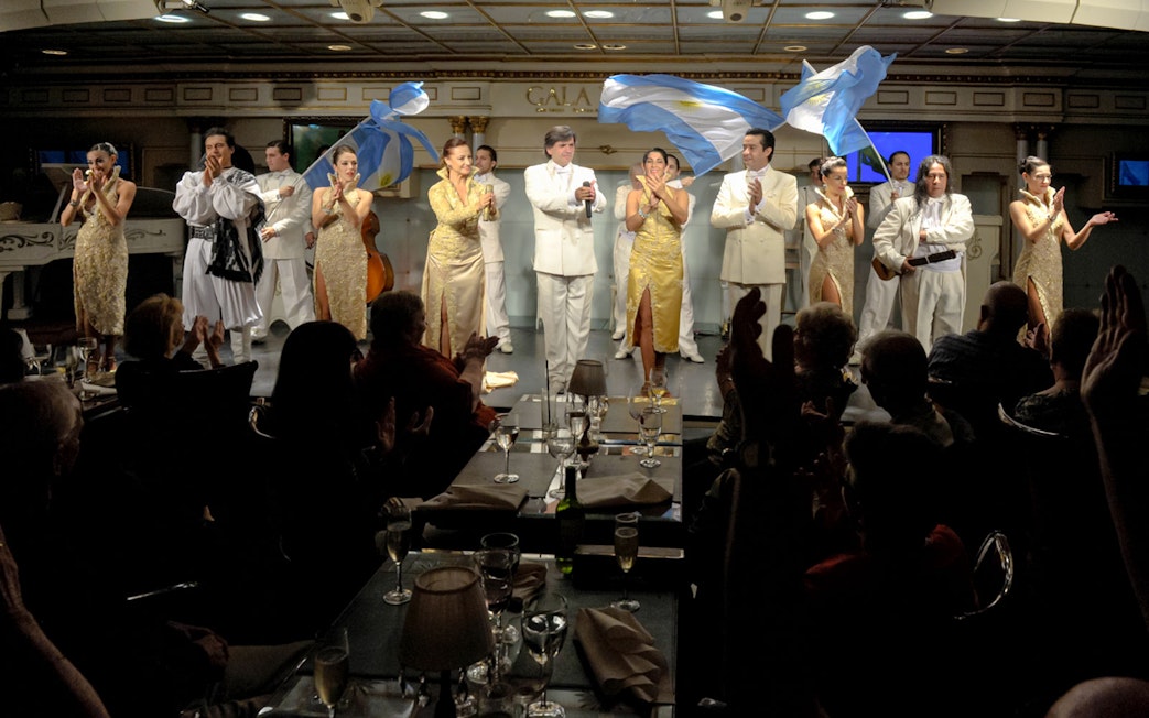 Performers on stage at Gala Tango Show in Buenos Aires, Argentina, with audience clapping.