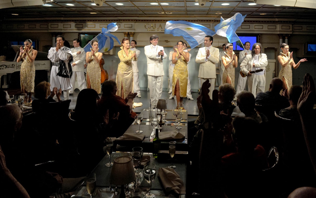 Performers on stage at Gala Tango Show in Buenos Aires, Argentina, with audience clapping.
