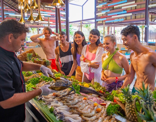 Chef serving seafood to tourists at Andamanda Phuket tropical beach.