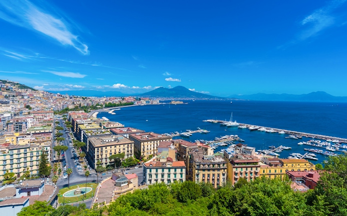Panoramic view of Naples cityscape with Mount Vesuvius in the background.