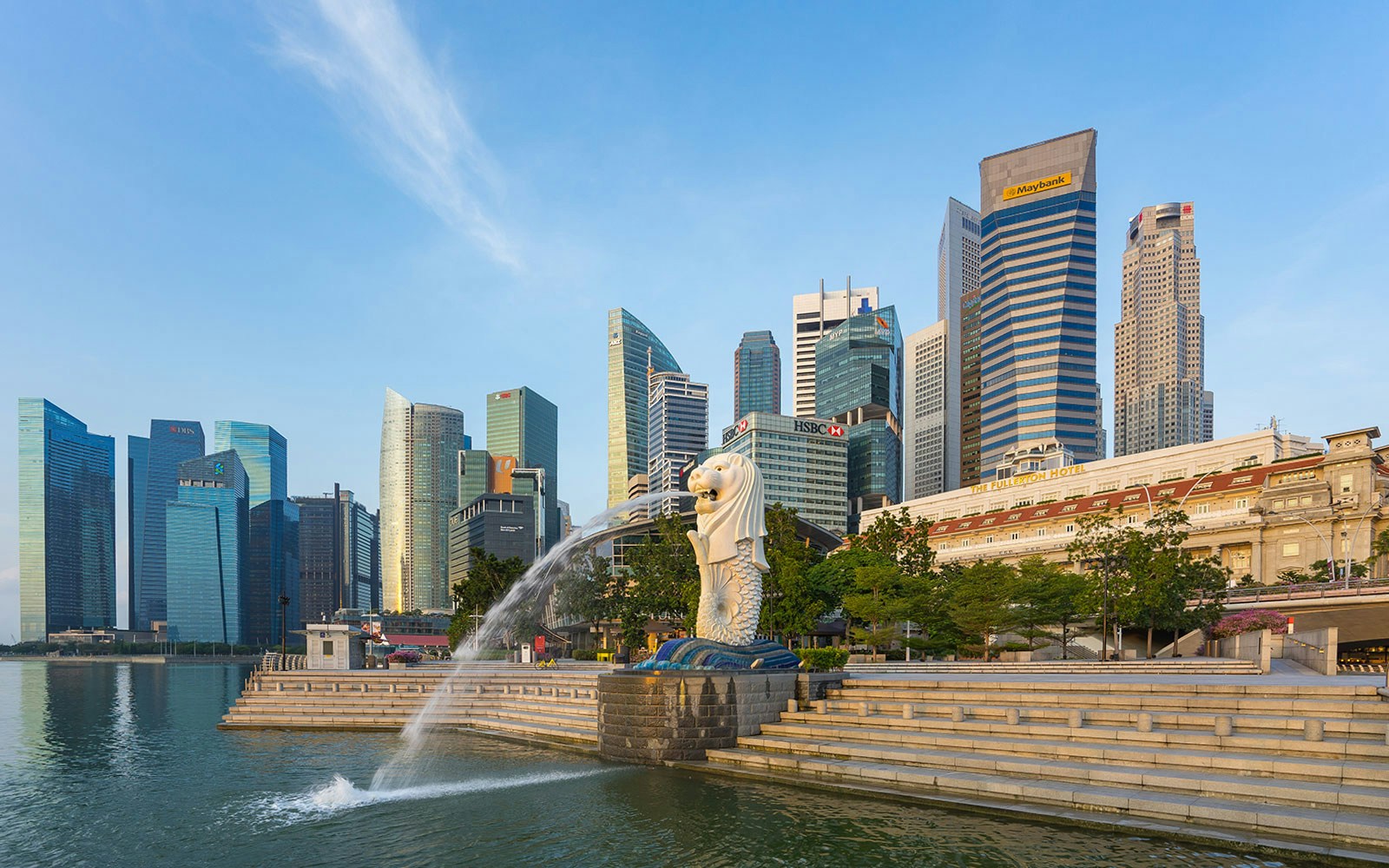 Merlion statue with city skyline and landmark buildings in Singapore's Merlion Park.