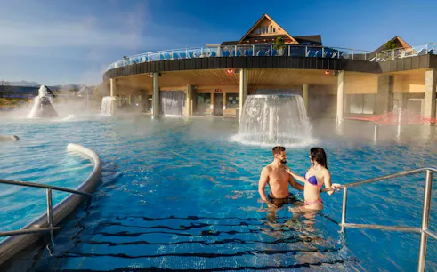 Couple enjoying Chochołów Thermal Baths with cascading water features.