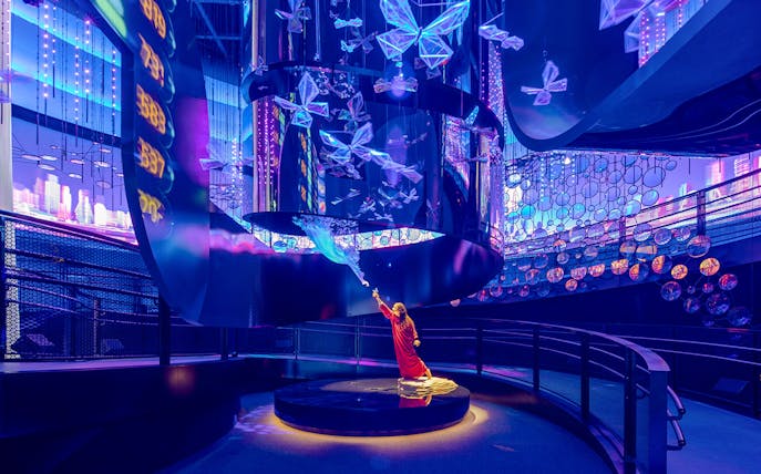 Child interacting with illuminated butterfly exhibit at Expo City Dubai.