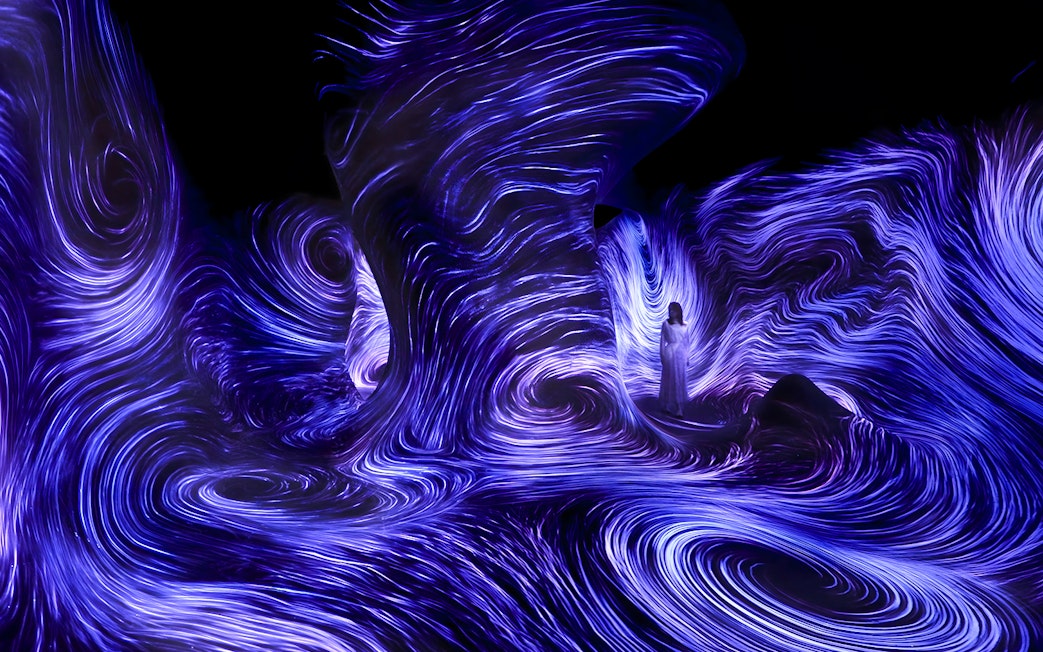 Immersive light installation at TeamLab Phenomena Abu Dhabi with swirling blue patterns.