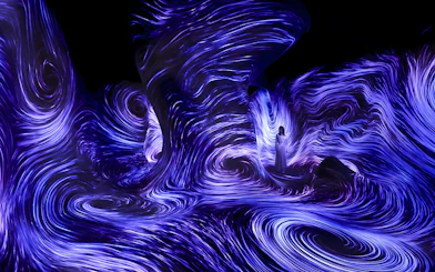 Immersive light installation at TeamLab Phenomena Abu Dhabi with swirling blue patterns.