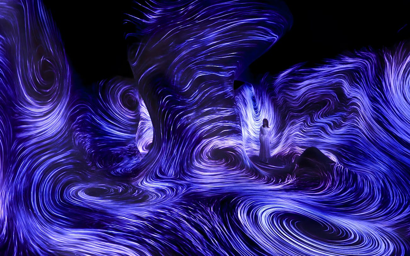 Immersive light installation at TeamLab Phenomena Abu Dhabi with swirling blue patterns.