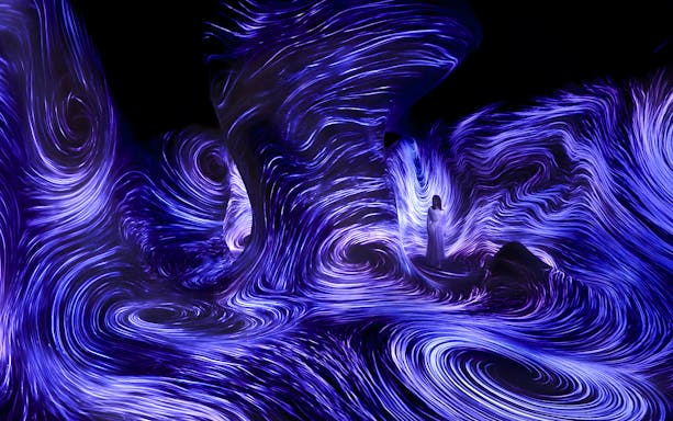 Immersive light installation at TeamLab Phenomena Abu Dhabi with swirling blue patterns.