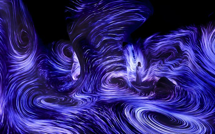 Immersive light installation at TeamLab Phenomena Abu Dhabi with swirling blue patterns.