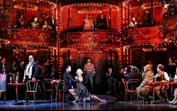 Opera performance of La Bohème with actors on stage and audience in ornate theater.