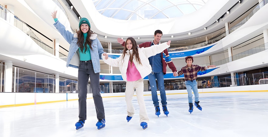Family ice skating at the American Dream ice rink under a glass dome.